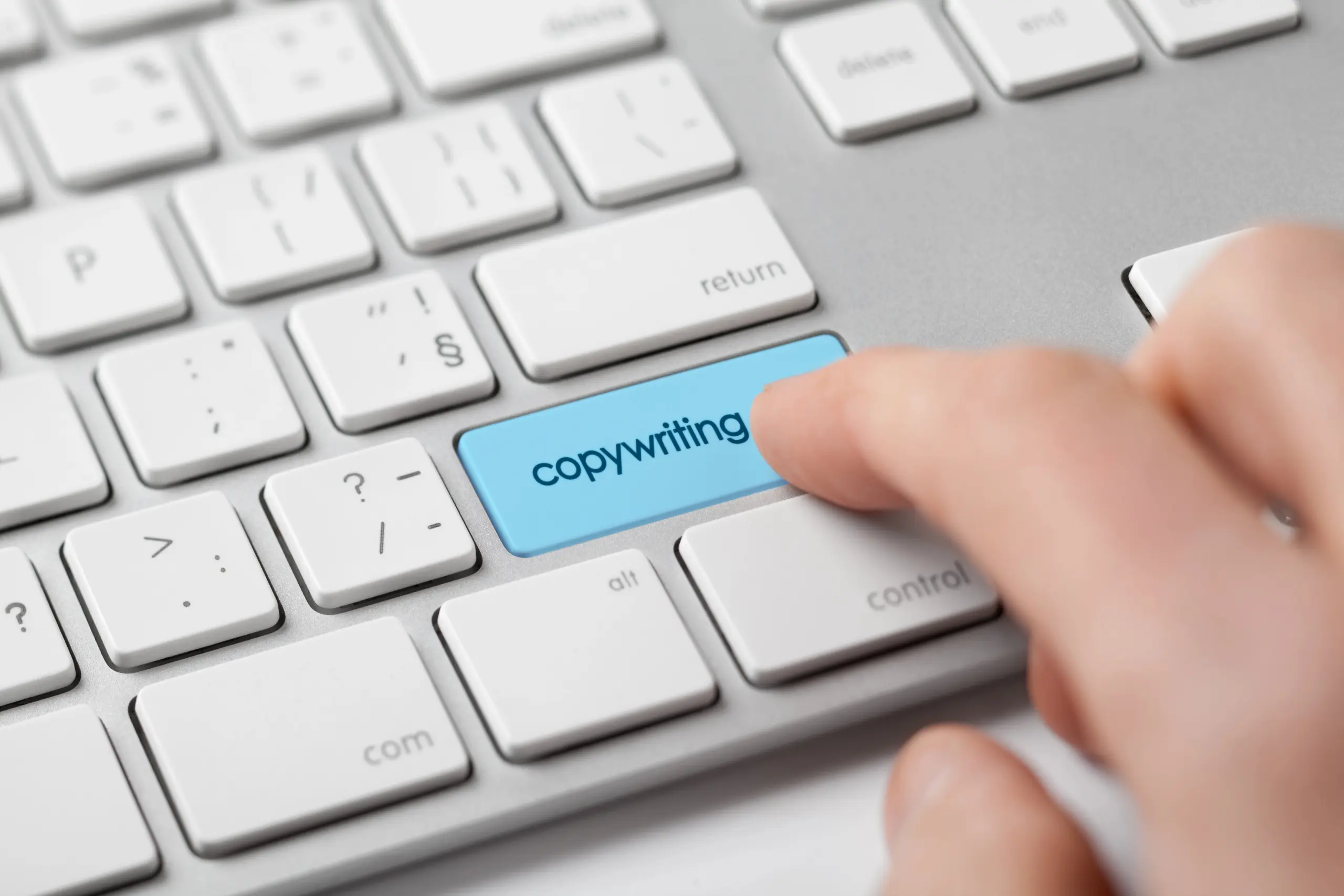 Finger pressing a blue copywriting key on a keyboard